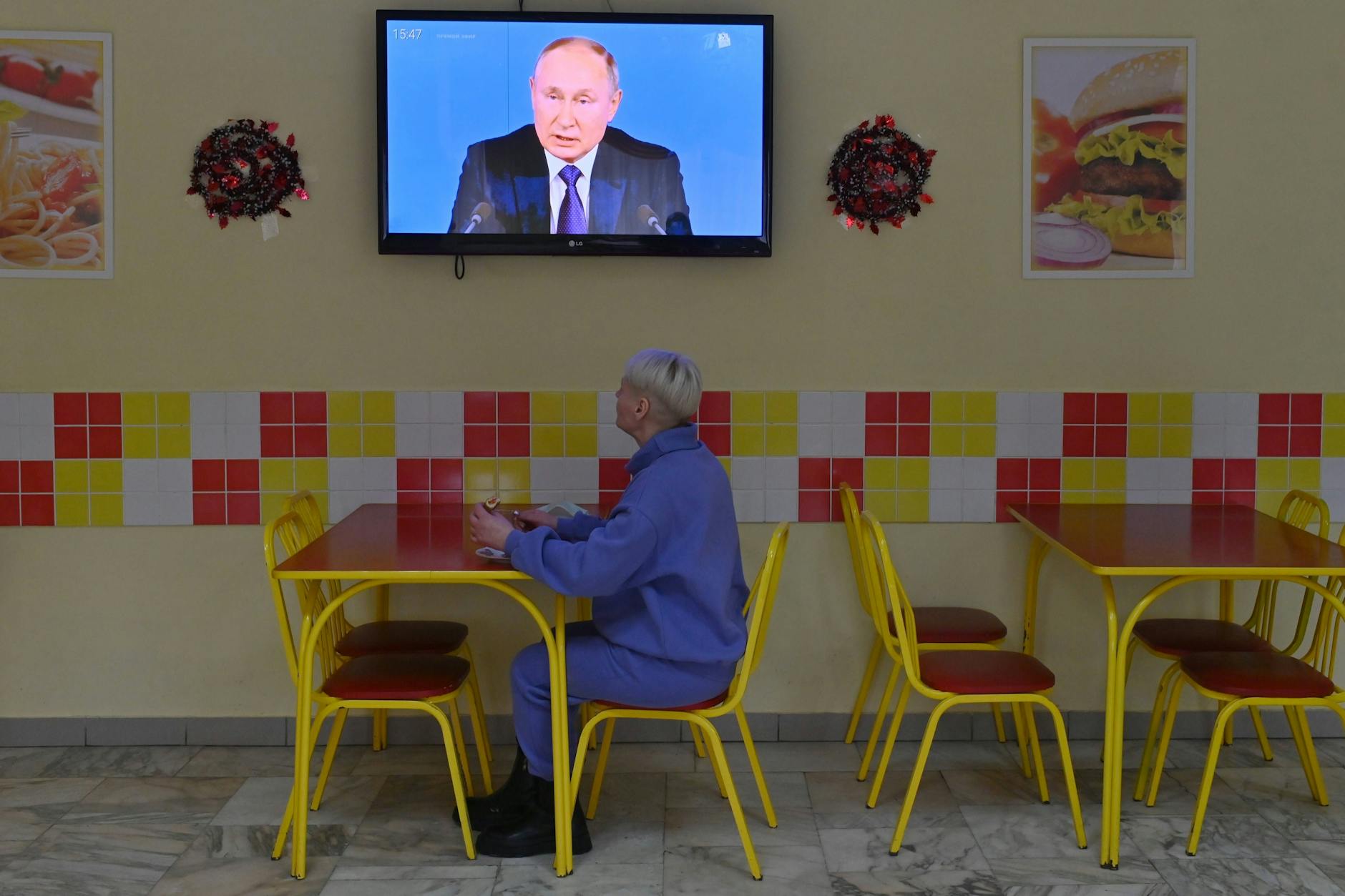 Eine Frau verfolgt im Restaurant eine Fernsehübertragung mit dem russischen Präsidenten Wladimir Putin.