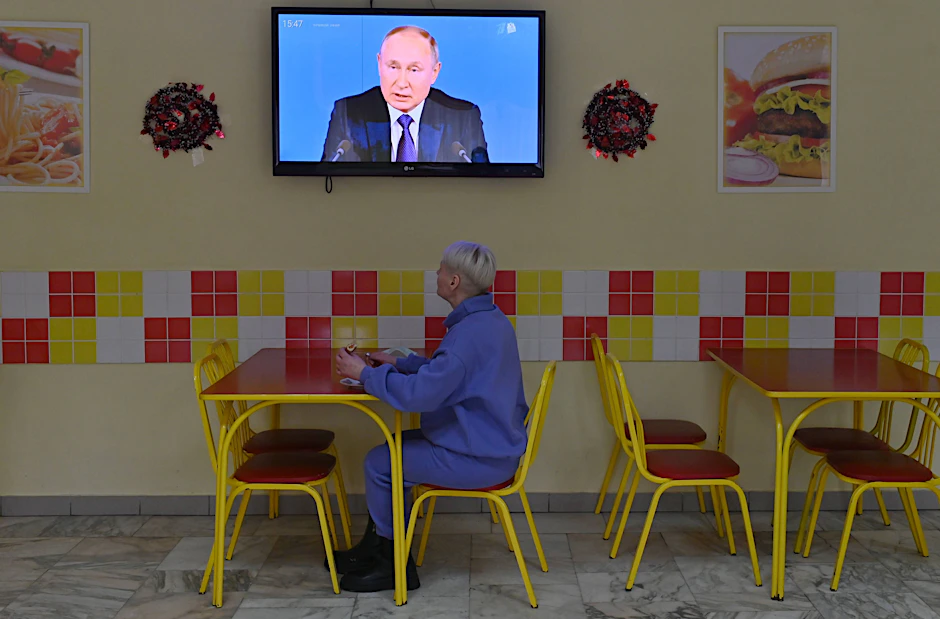 Eine Frau verfolgt im Restaurant eine Fernsehübertragung mit dem russischen Präsidenten Wladimir Putin.