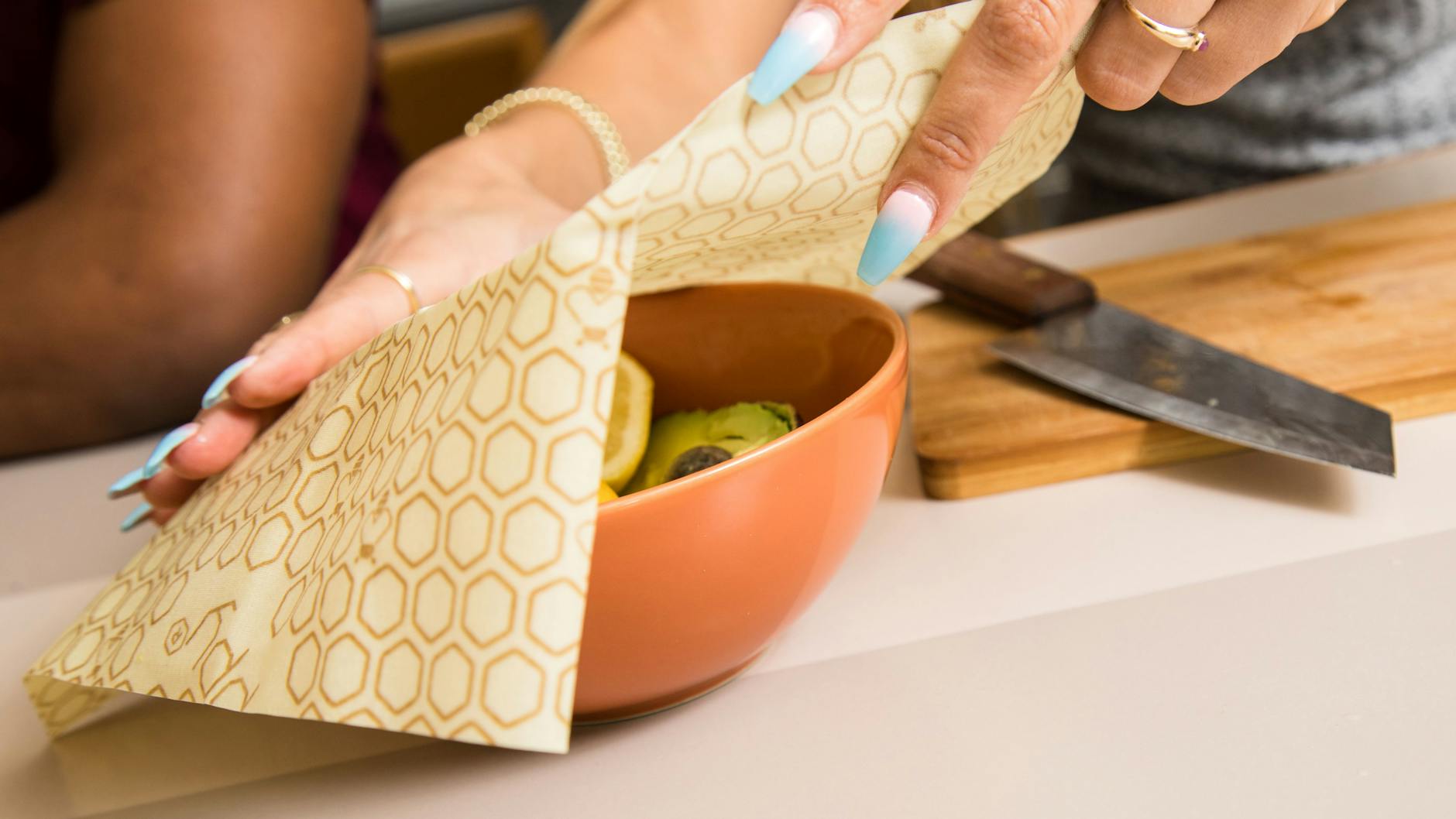 Eine Frau deckt eine Schüssel mit Avocados mit einem Bienenwachstuch ab, um sie frisch zu halten.