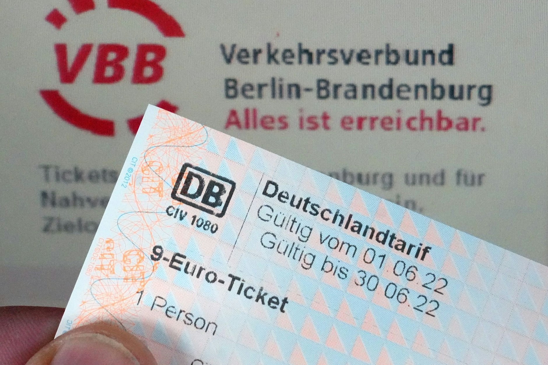 Ein Glücklicher hält auf dem Potsdamer Hauptbahnhof ein 9-Euro-Ticket vor einem Ticketautomaten.