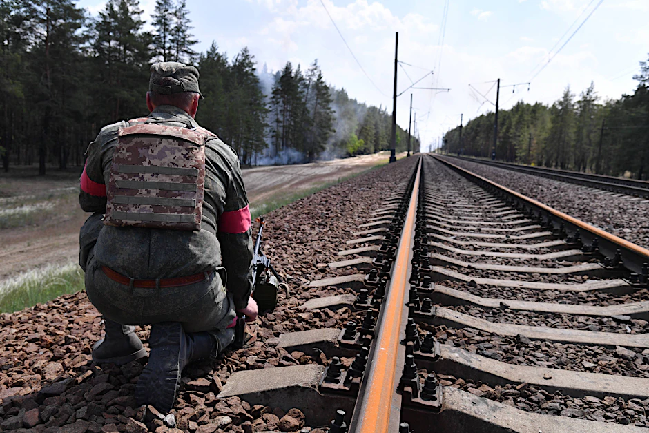Ein Mann in Militäruniform hockt neben Bahngleisen in der Ukraine (Symbolbild).