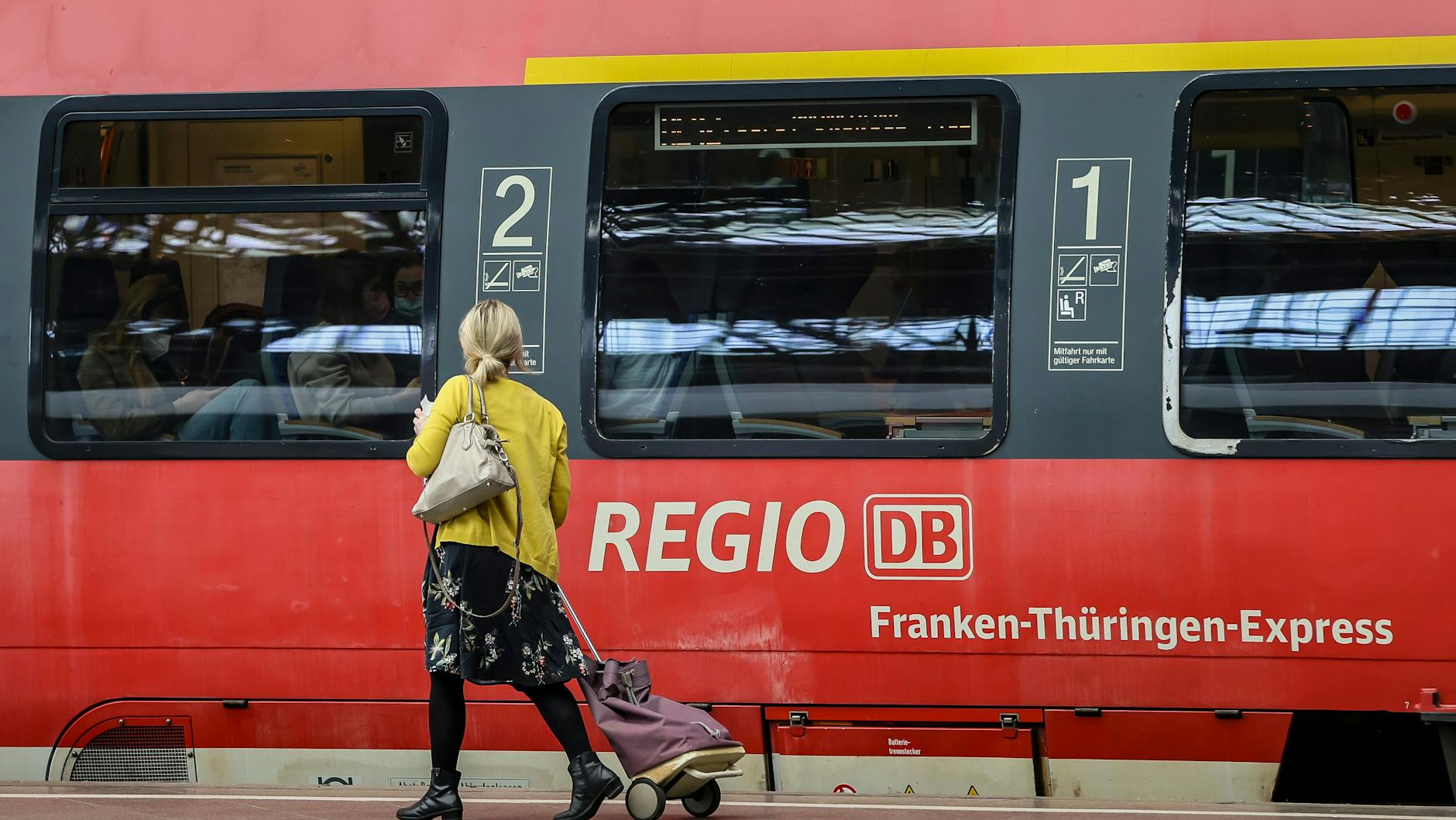 Eine Frau geht an einem Regionalexpress entlang.
