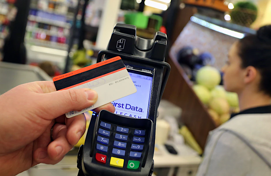 Eine Karte wird an den Bezahl-Terminal an der Kasse eines Supermarktes gehalten.