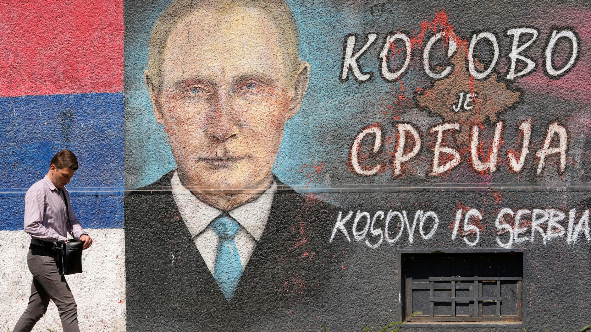 Belgrad, 13. Mai 2022: Ein Mann geht an einem Graffiti an einer Wand vorbei, das den russischen Präsidenten Wladimir Putin und die serbische Flagge. Die kyrillische Schrift lautet: „Kosovo ist Serbien“. Serbien hat sich der Verurteilung des russischen Angriffs durch die Vereinten Nationen angeschlossen, weigert sich jedoch, Sanktionen gegen Moskau zu verhängen.