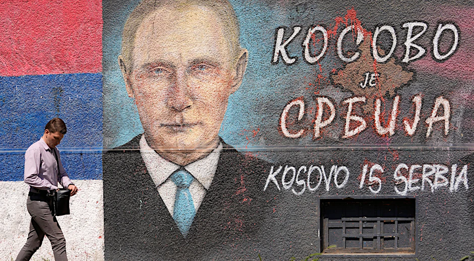 Belgrad, 13. Mai 2022: Ein Mann geht an einem Graffiti an einer Wand vorbei, das den russischen Präsidenten Wladimir Putin und die serbische Flagge. Die kyrillische Schrift lautet: „Kosovo ist Serbien“. Serbien hat sich der Verurteilung des russischen Angriffs durch die Vereinten Nationen angeschlossen, weigert sich jedoch, Sanktionen gegen Moskau zu verhängen.