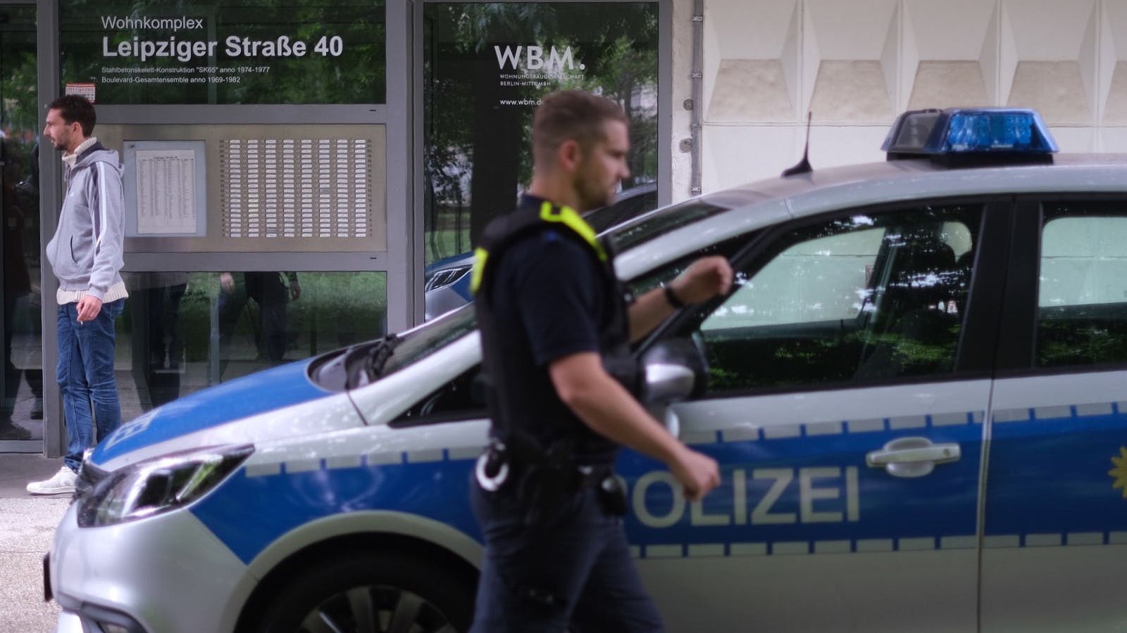 Polizeibeamte stehen vor dem Haus an der Leipziger Straße, in dem es am Samstag einen Rohrbruch gegeben hatte.