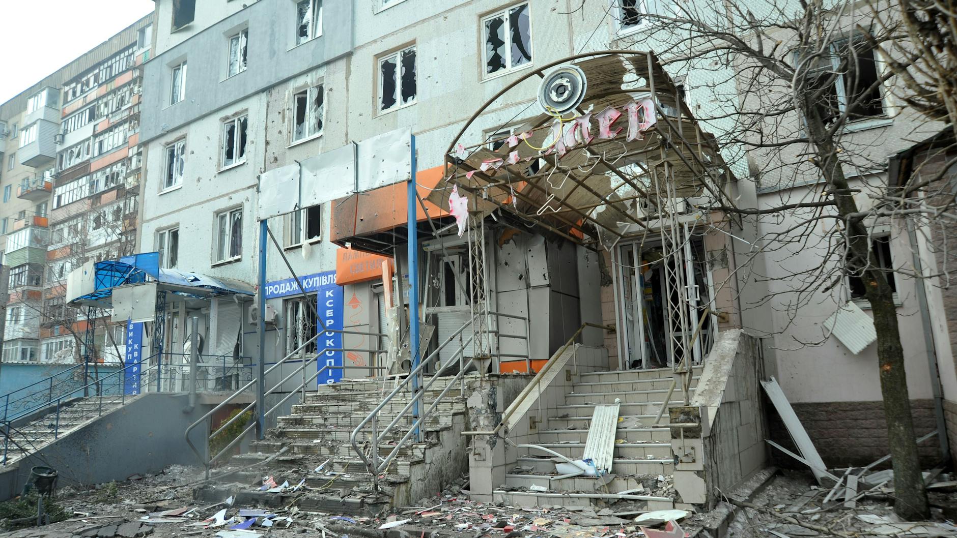 Blick auf Geschäfte im Erdgeschoss und ein Wohnhaus in Sjewjerodonezk, die durch den Beschuss durch russische Truppen beschädigt wurden.