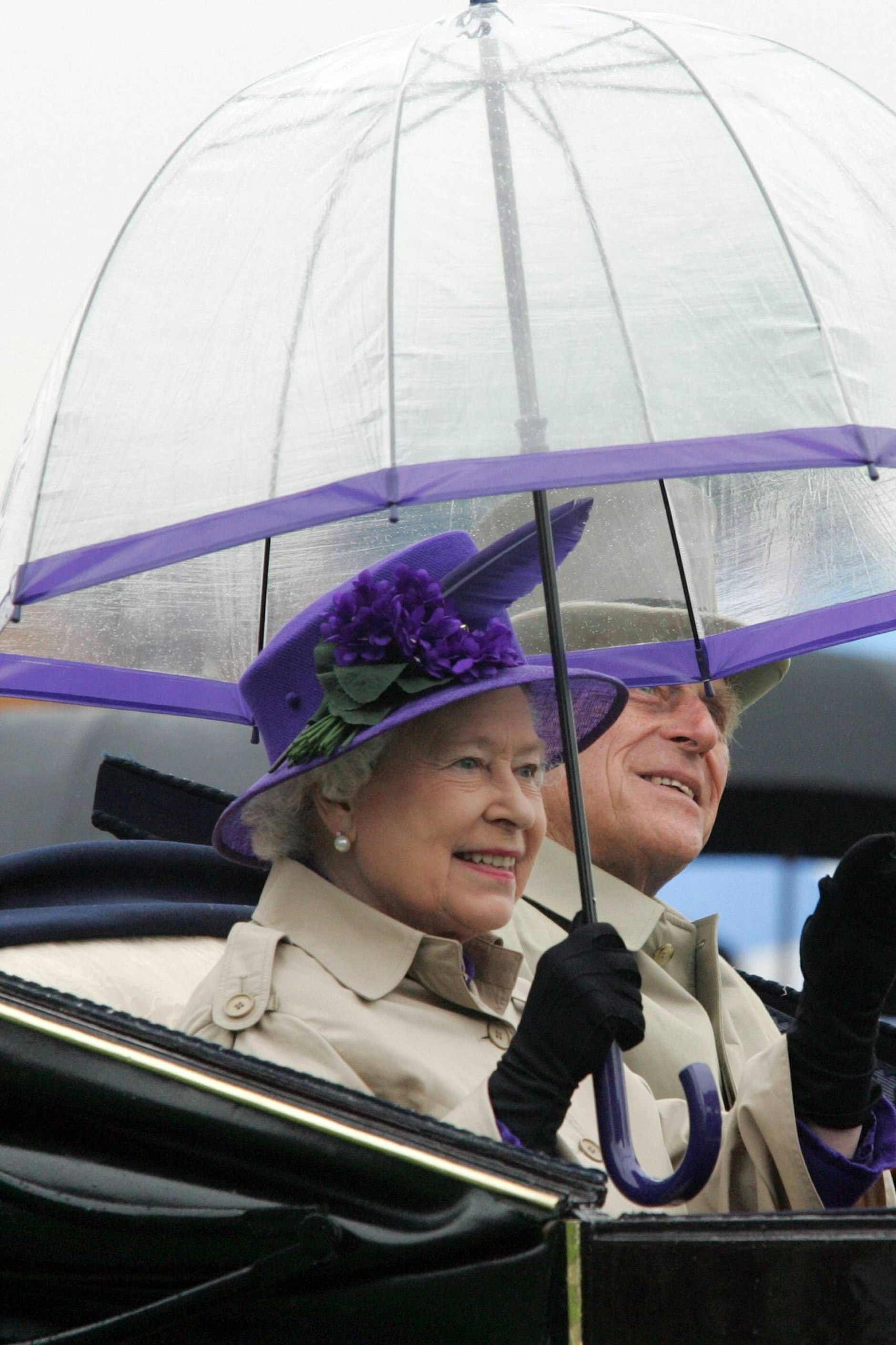 Adel verpflichtet: Zum lilafarbenen Hut ein Schirm mit lila Rändern.