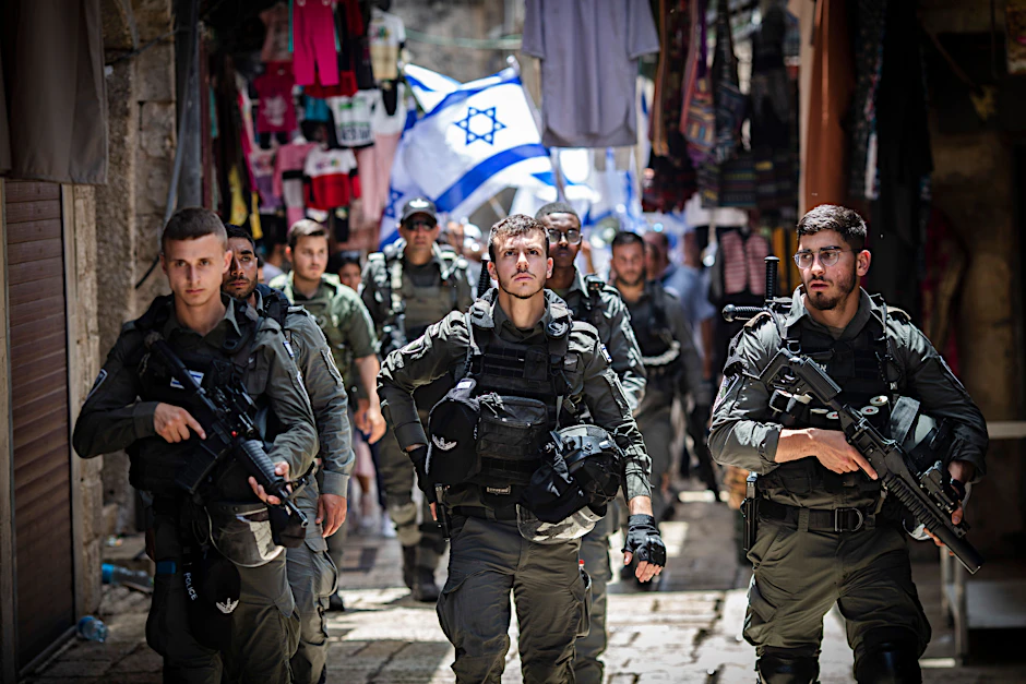 Israelische Polizisten sichern Israelis, die im Mai 2022 am Jerusalem-Tag mit ihren Nationalflaggen durch die Altstadt von Jerusalem gehen.