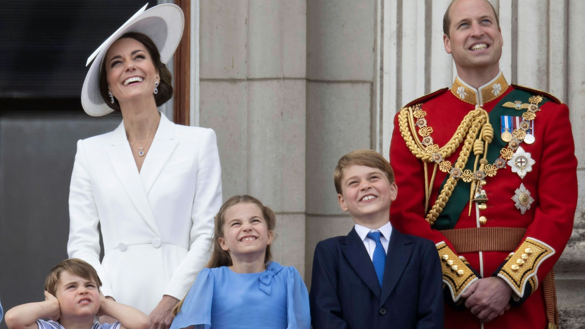 Prinz William und seine Frau Kate stehen mit ihren Kindern George, Charlotte und Louis auf dem Balkon des Buckingham Palastes und verfolgen die Geschehnisse am Himmel. Dem vierjährigen Louis ist es offenbar zu laut.