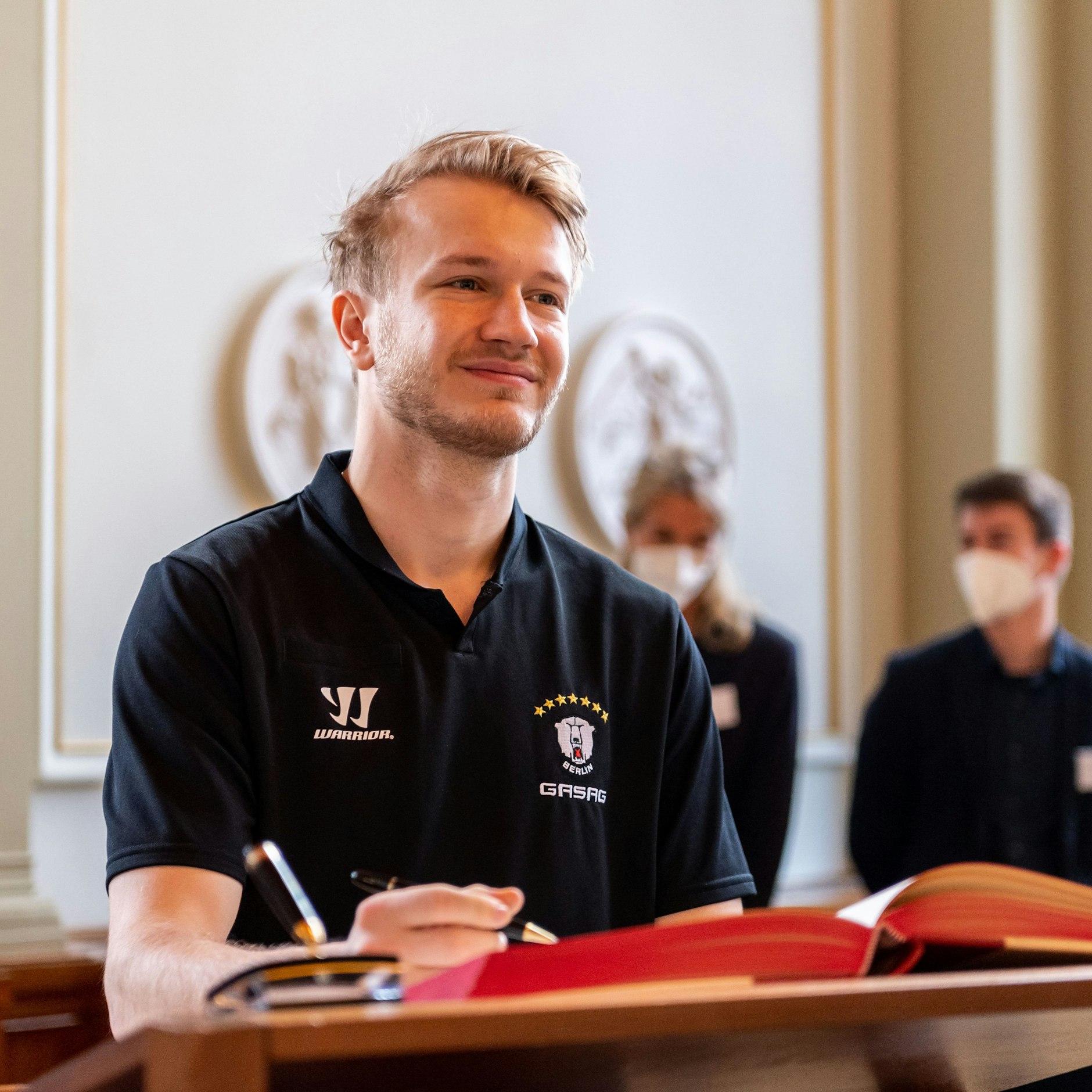 Eisbär Eric Mik verewigt sich im roten Rathaus im Goldenen Buch der Stadt.