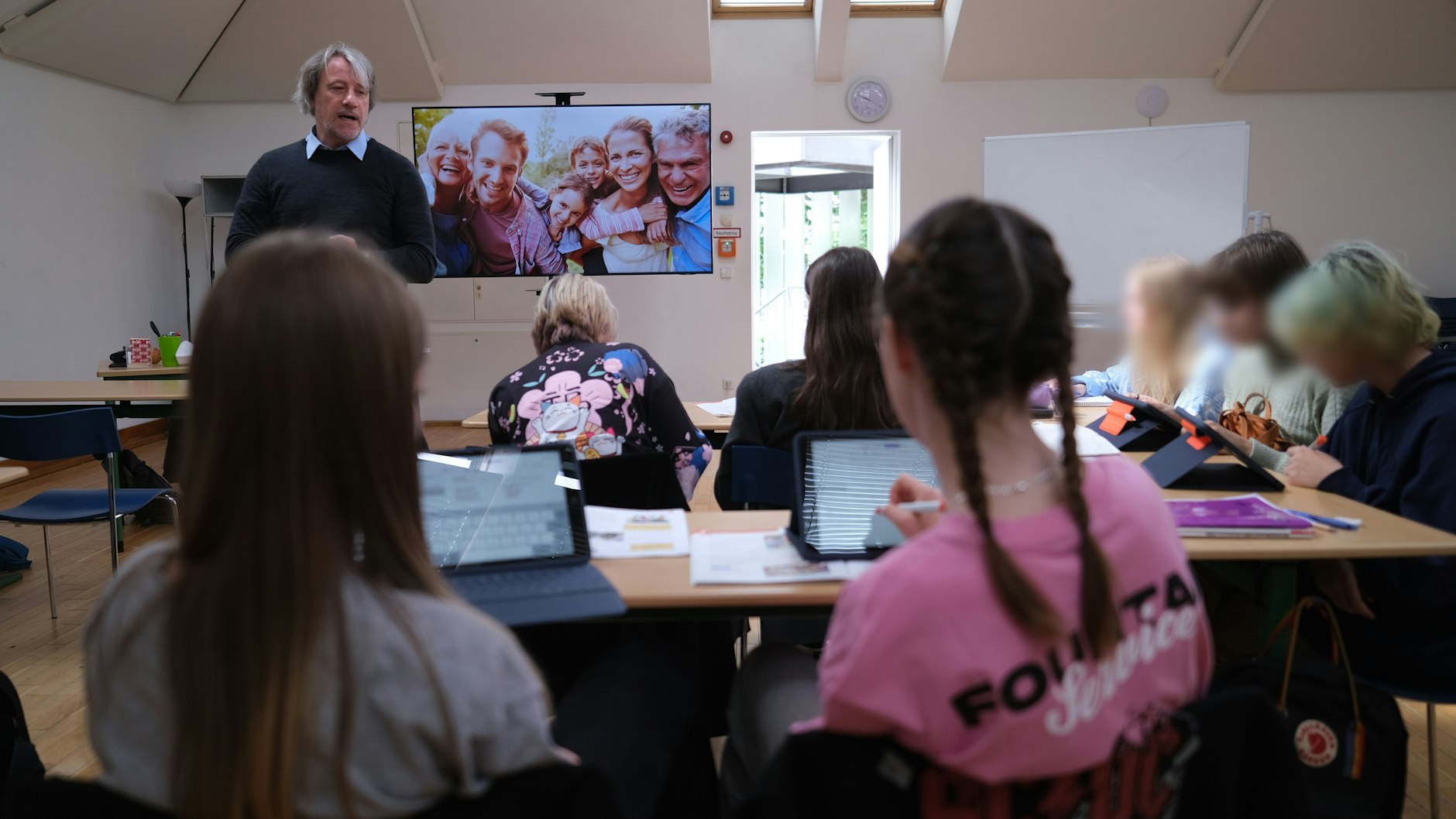 Die neue Willkommensklasse am Canisius-Kolleg: Jan Gursch-Büdenbender fragt seine ukrainischen Schüler, wie die Personen auf dem großen Familienfoto heißen.