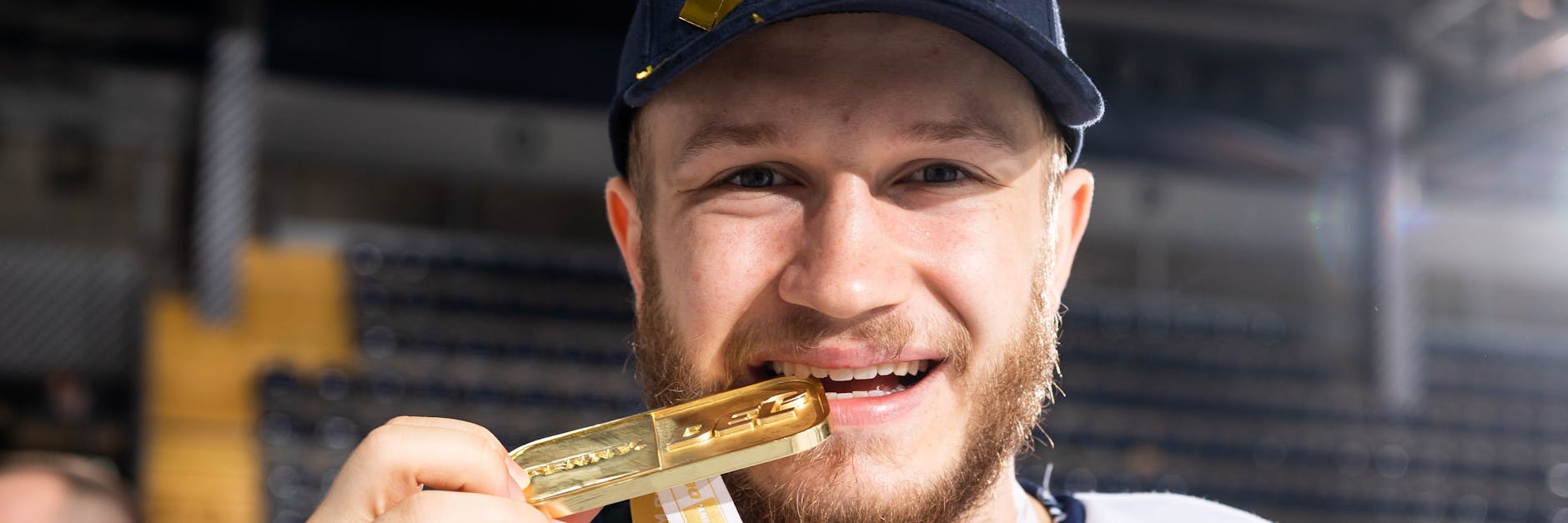 Eisbär Eric Mik macht den Bisstest: Die Meister-Goldmedaille ist echt.