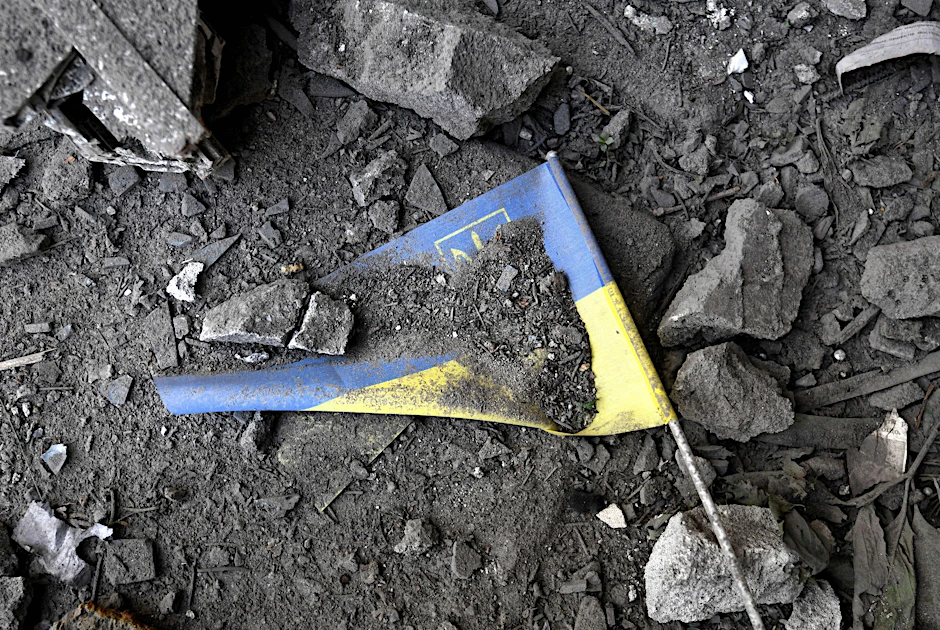 Eine ukrainische Fahne liegt nach einem Raketeneinschlag in den Trümmern eines Hauses.