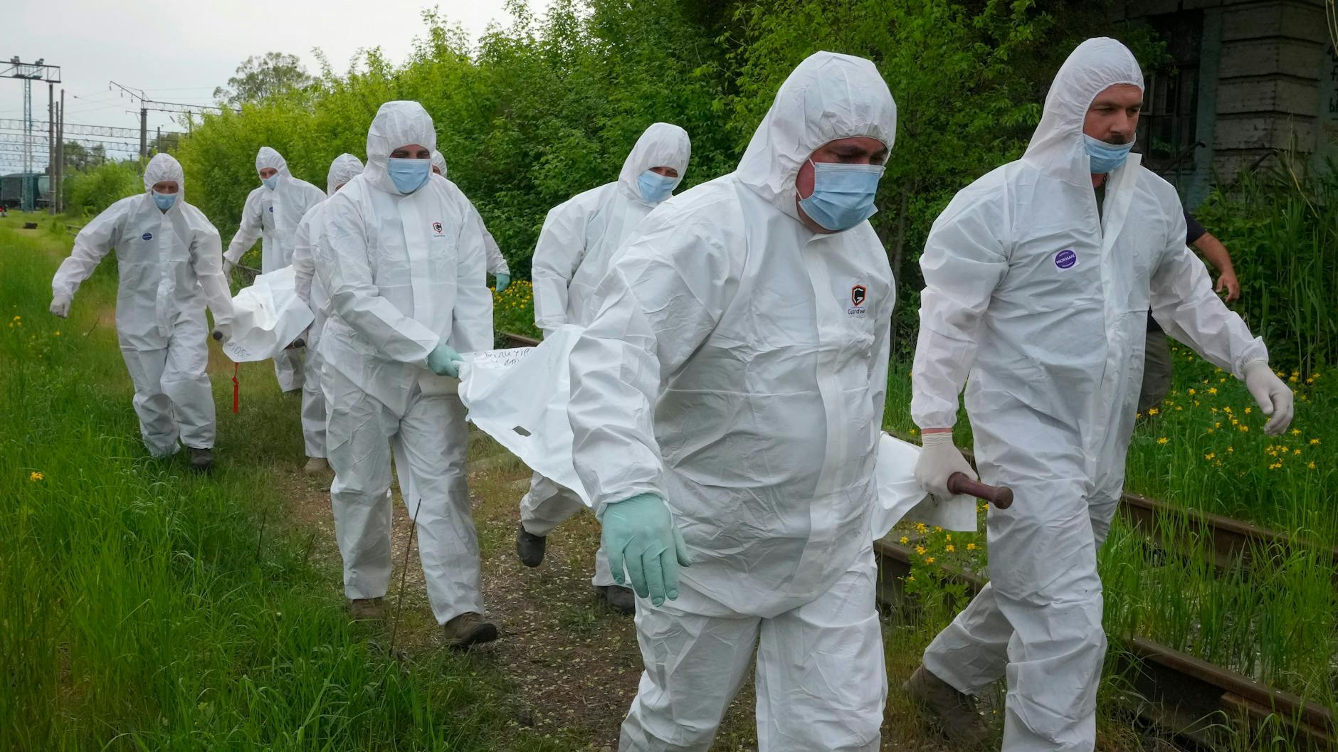 Ukrainische Soldaten tragen die Leichen russischer Soldaten, um sie in den Kühlwagen eines Zuges zu laden.