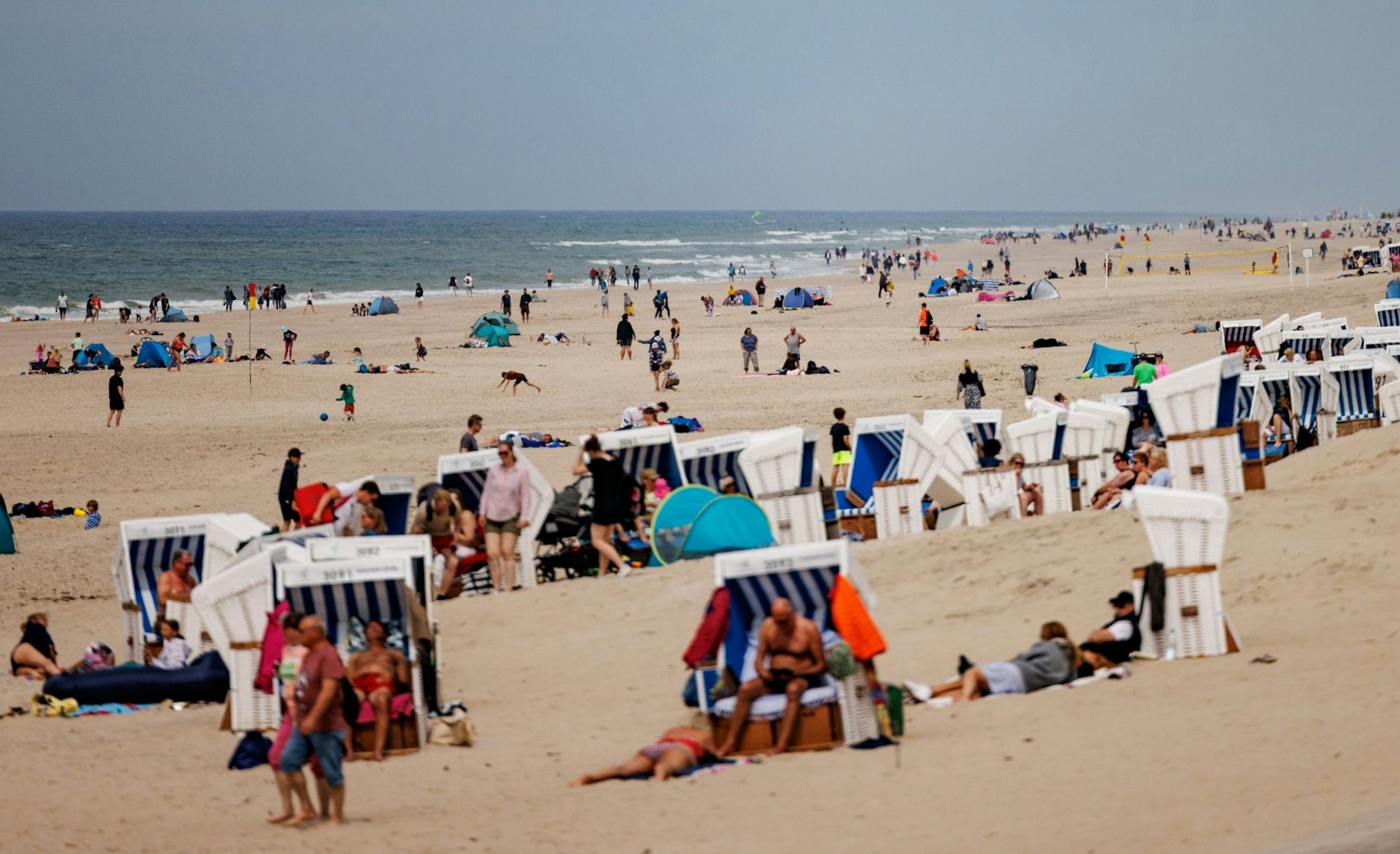 Besucher der Insel Sylt liegen in der strahlenden Sonne am Strand.  