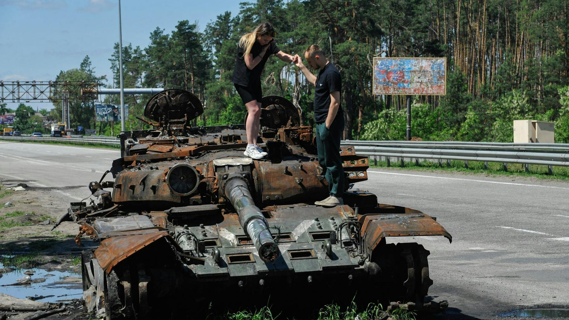 Etwa 40 Kilometer westlich von Kiew inspizieren zwei junge Menschen einen zerstörten Panzer der russischen Armee.