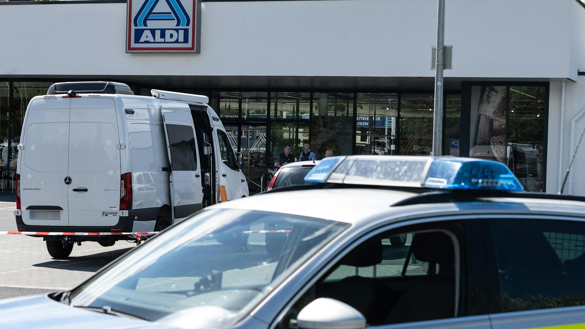 Schwalmstadt: Einsatzfahrzeuge der Polizei stehen vor dem abgesperrten Einkaufsmarkt.