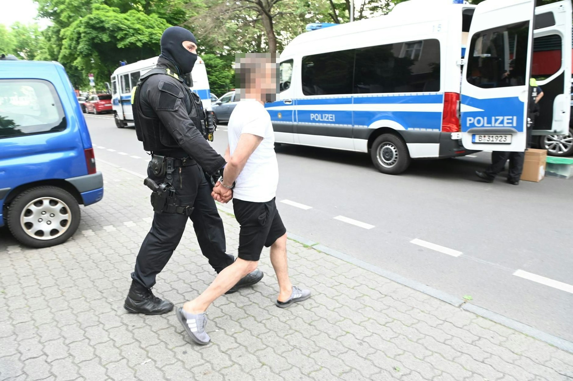 Ein Mann in Hausschuhen wird gefesselt in der Bülowstraße abgeführt.