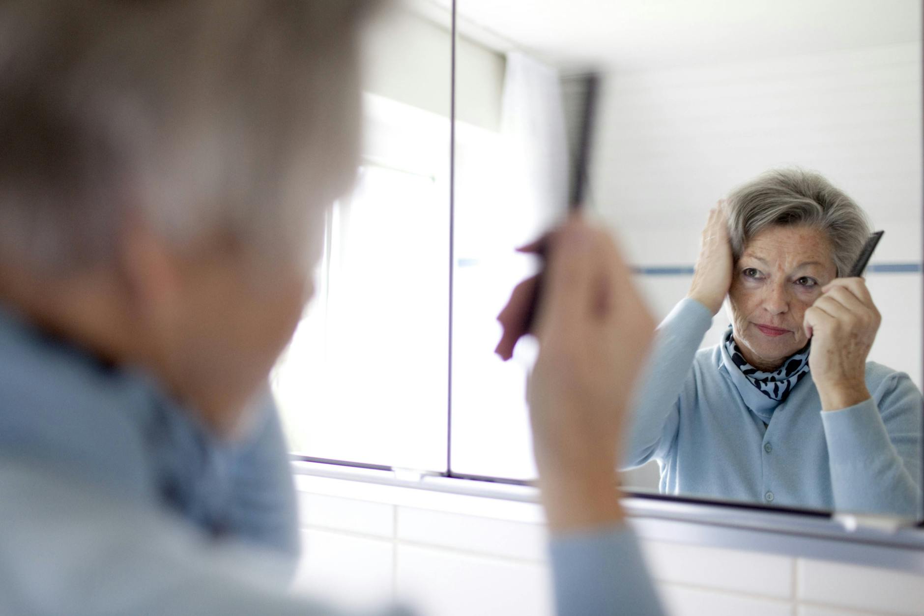 Kritischer Blick in den Spiegel: Ausfallende Haare werden offensichtlich, wenn die Kopfhaut durchscheint.