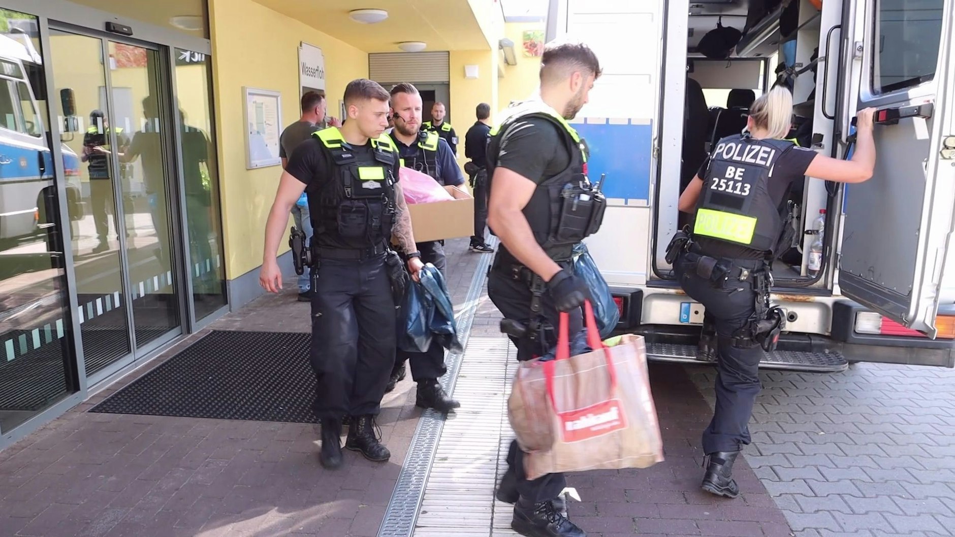 Polizisten tragen Drogen und andere Beweismittel aus dem Schwimmbad an der Lipschitzallee.
