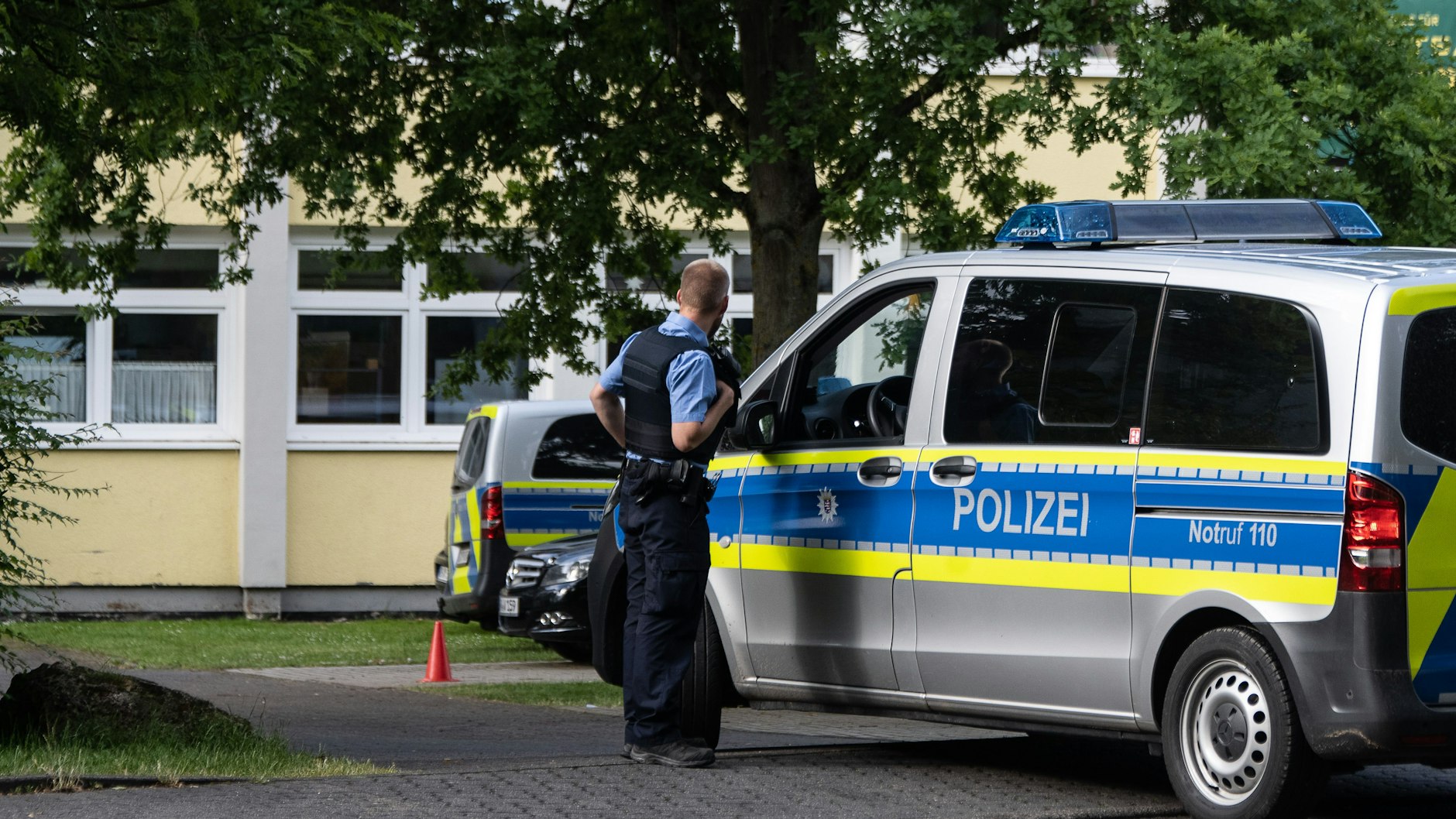 Ein Polizist steht an einem Einsatzfahrzeug vor der Haupt- und Realschule Kaulbach-Schule im nordhessischen Bad Arolsen.
