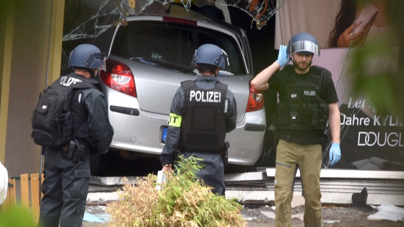 Nach der Amokfahrt sichern Polizisten den Tatort. Im Hintergrund das Tatfahrzeug.