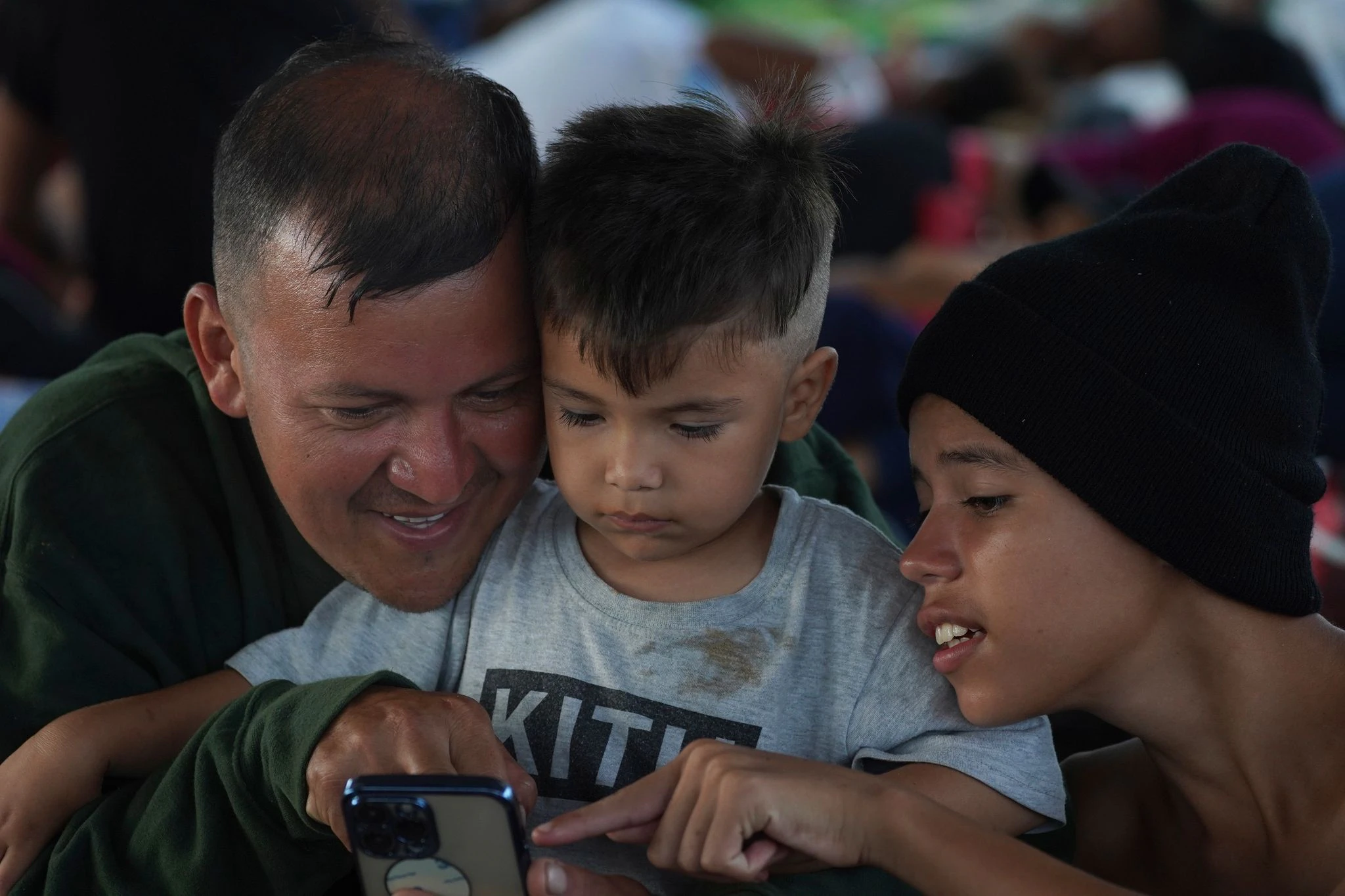 Der Venezolaner Eymar Hernandez und seine Söhne Santiago (M.) und Carlos (r), die Teil einer Migrantenkarawane sind, schauen sich Inhalte auf einem Smartphone an. Alle drei gehören zu einer 18-köpfigen Großfamilie, darunter acht Kinder, die innerhalb von 15 Tagen bis zur südlichen Grenze Mexikos gereist sind.  