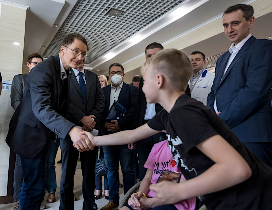 Bundesgesundheitsminster Karl Lauterbach (l) beim Klinikbesuch in Lwiw. Er begrüßt einen Jungen, dessen Mutter und Schwester bei einem Bombenangriff schwer verletzt wurden und hier behandelt werden.