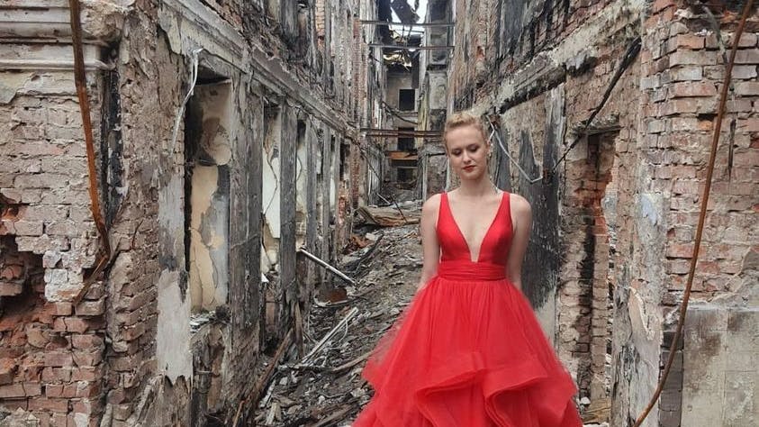 Eine Abiturientin aus Charkiw, Ukraine, posiert in ihrem Abiball-Kleid in den Ruinen ihrer Schule.