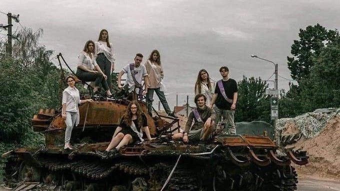 Ukrainische Abiturienten posieren in Charkiw auf einem zerstörten Panzer.