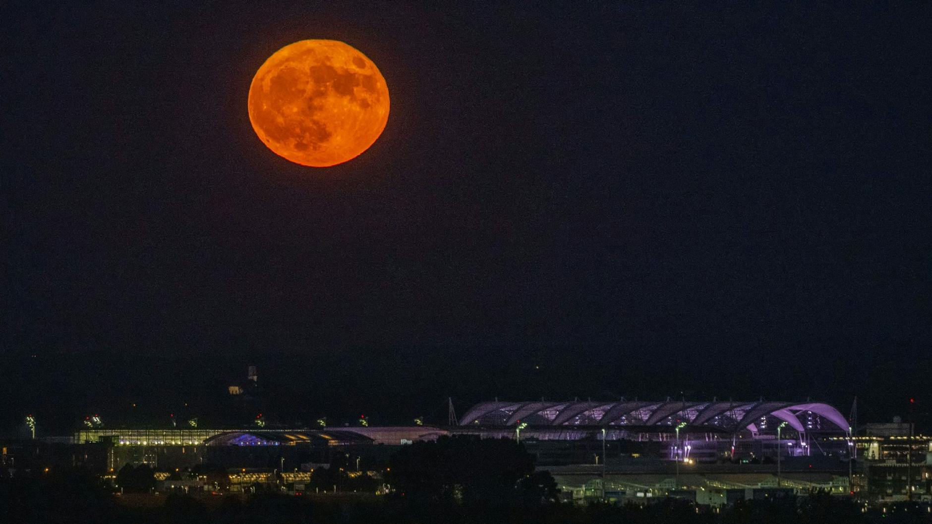 Der rötliche Vollmond ging am Abend über dem Flughafen München auf.
