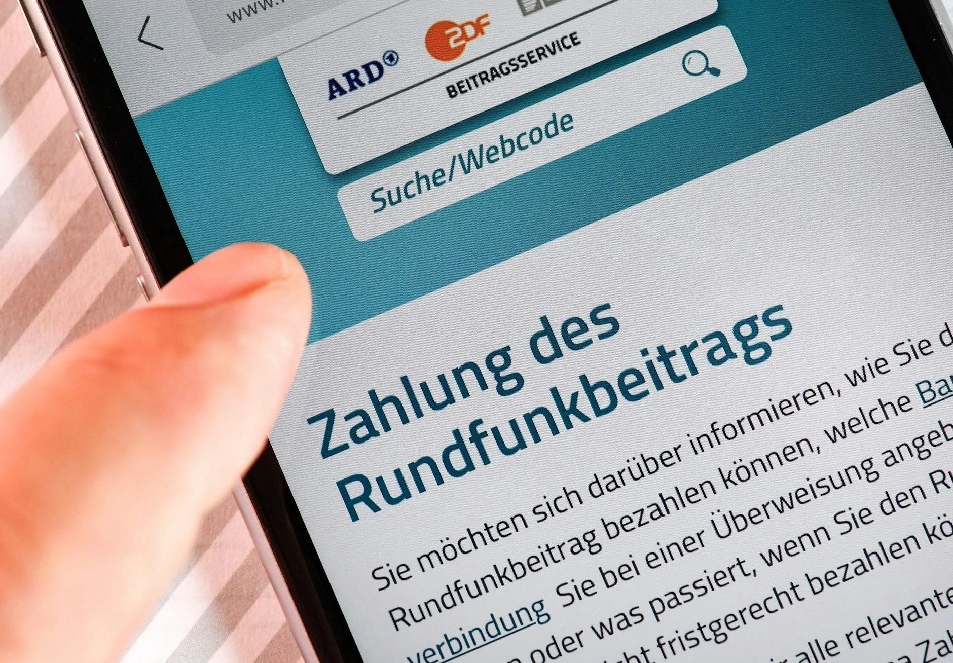 ARCHIV - Auf einem Smartphone ist eine Website zur Information über die Zahlung des Rundfunkbeitrags aufgerufen.