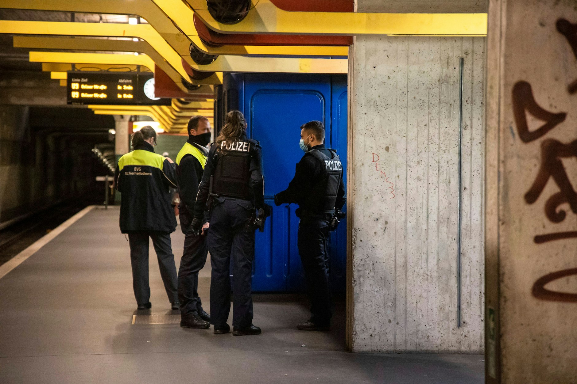 Mitarbeiter des BVG-Sicherheitsdienstes und Polizistenbei stehen auf einem U-Bahnhof.&nbsp;