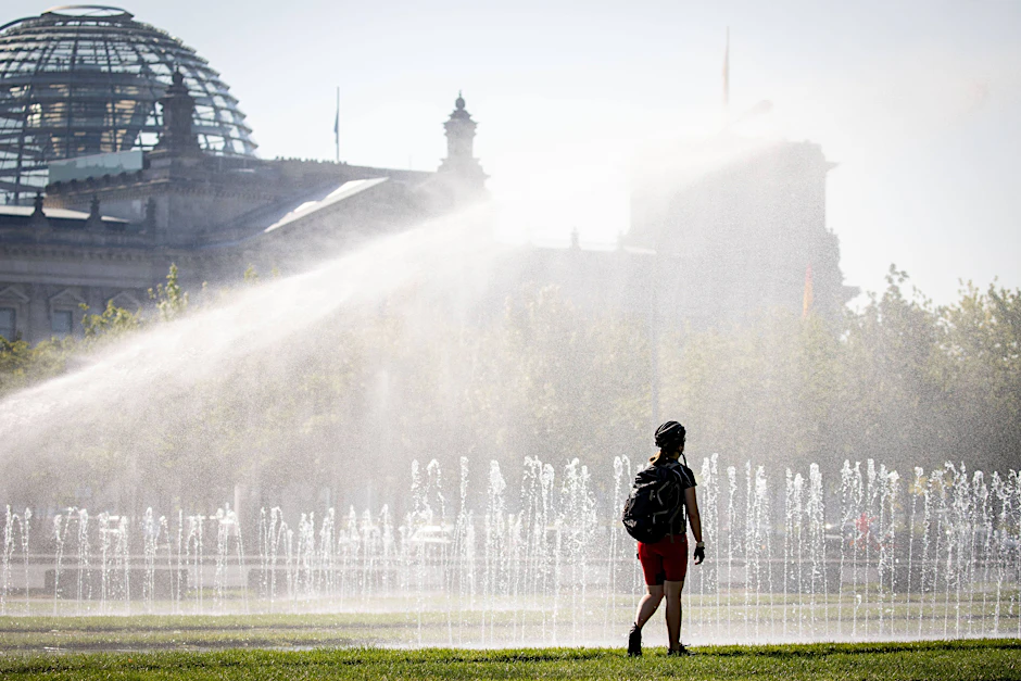 Eine Passantin erfrischt sich in einer Wasserfontäne vor dem Reichstag. In der Hauptstadt werden Temperaturen bis 37 Grad erwartet.