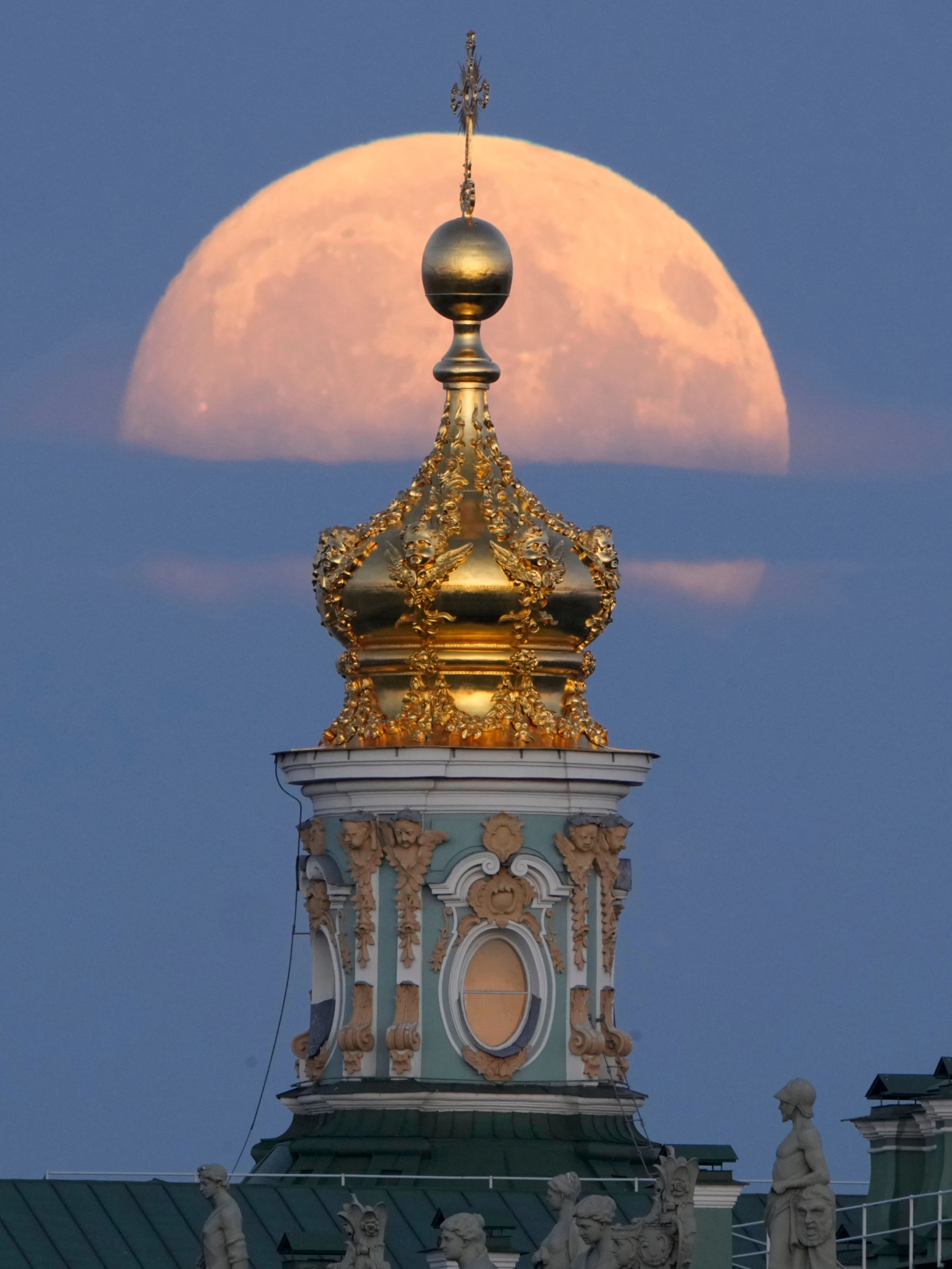 St. Petersburg in Russland: Der Vollmond geht verdeckt von Wolken über einer Kirche auf.