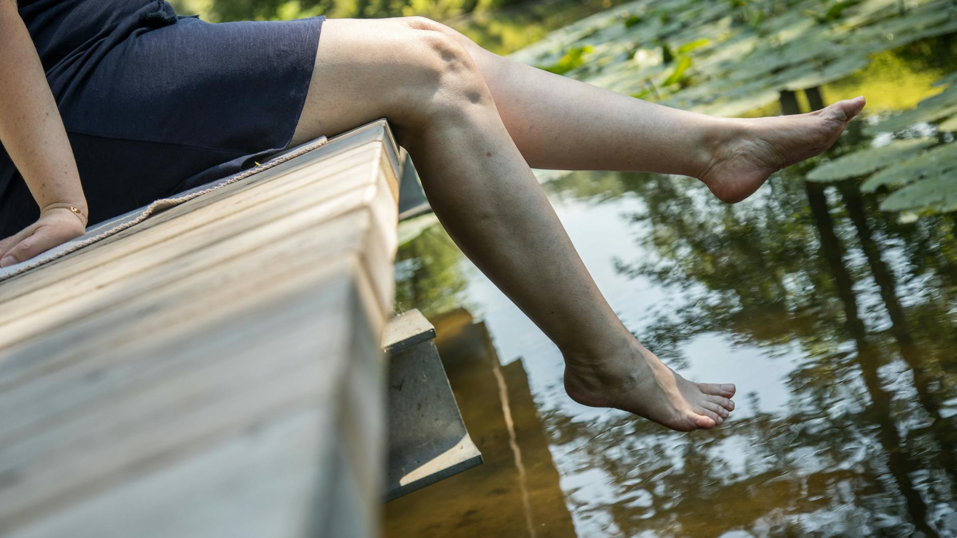 Eine Frau sitzt an einem Teich. (Symbolbild)