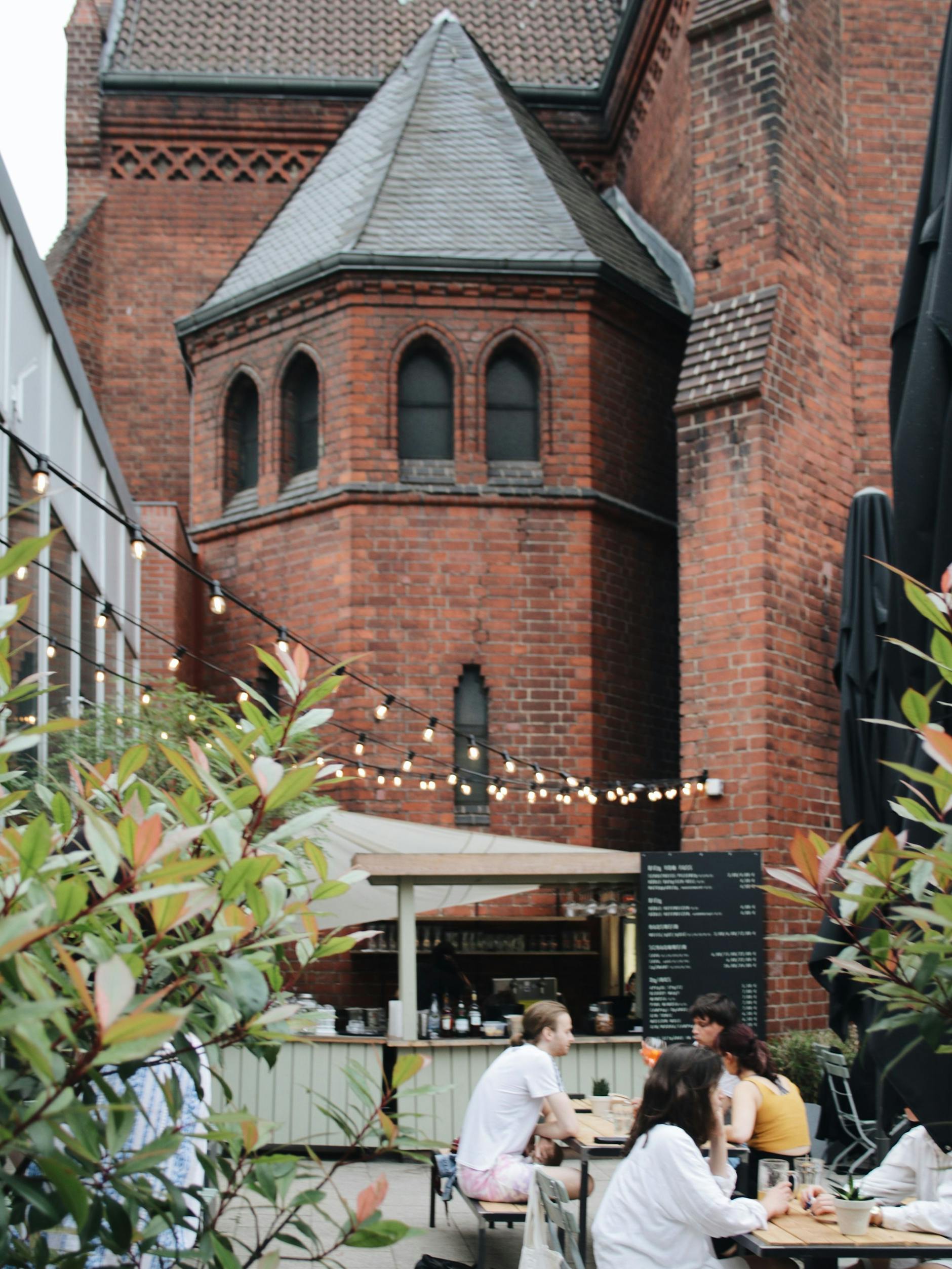 Mit der Kirche als Raum und als Kulisse am Herrfurthplatz: der Biergarten des Terz im Neuköllner Schillerkiez.