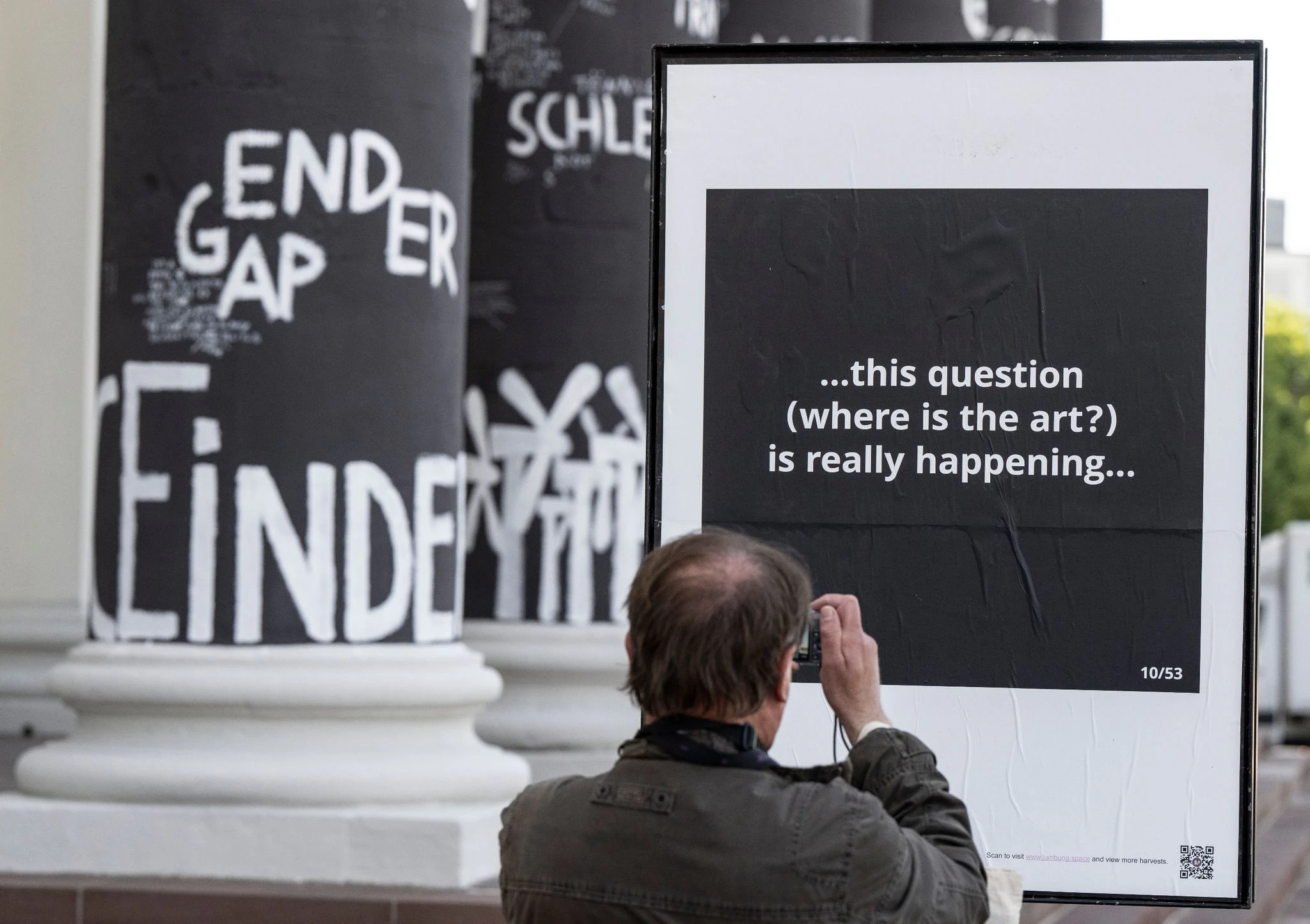 Ein Mann fotografiert auf dem Friedrichsplatz in Kassel ein Hinweisschild der Kunstausstellung documenta, die ab dem 18. Juni für allen Interessierten öffnet.  