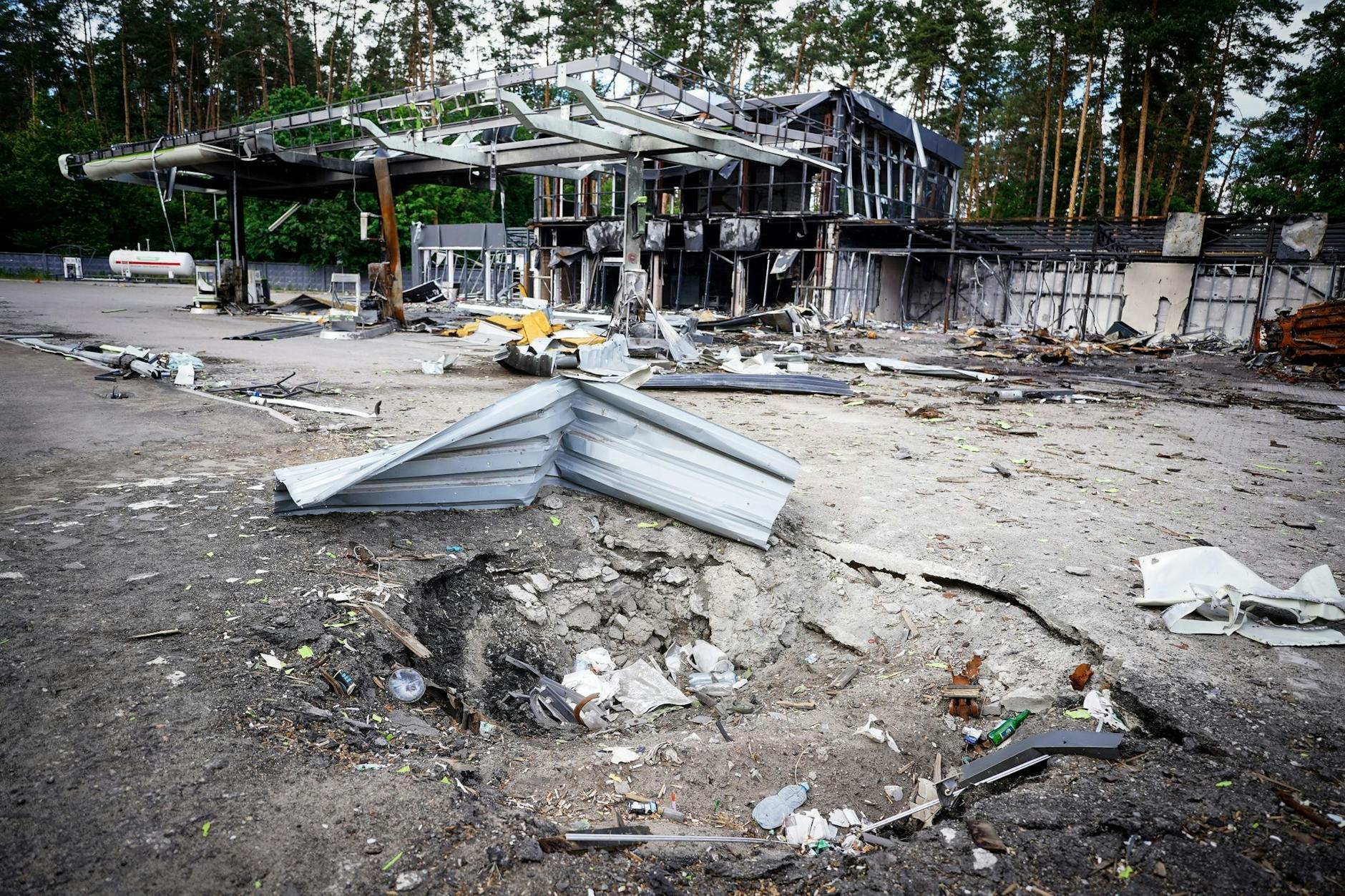 Ein Bombenkrater vor einer zerstörten Tankstelle am Stadtrand der ukrainischen Hauptstadt Kiew