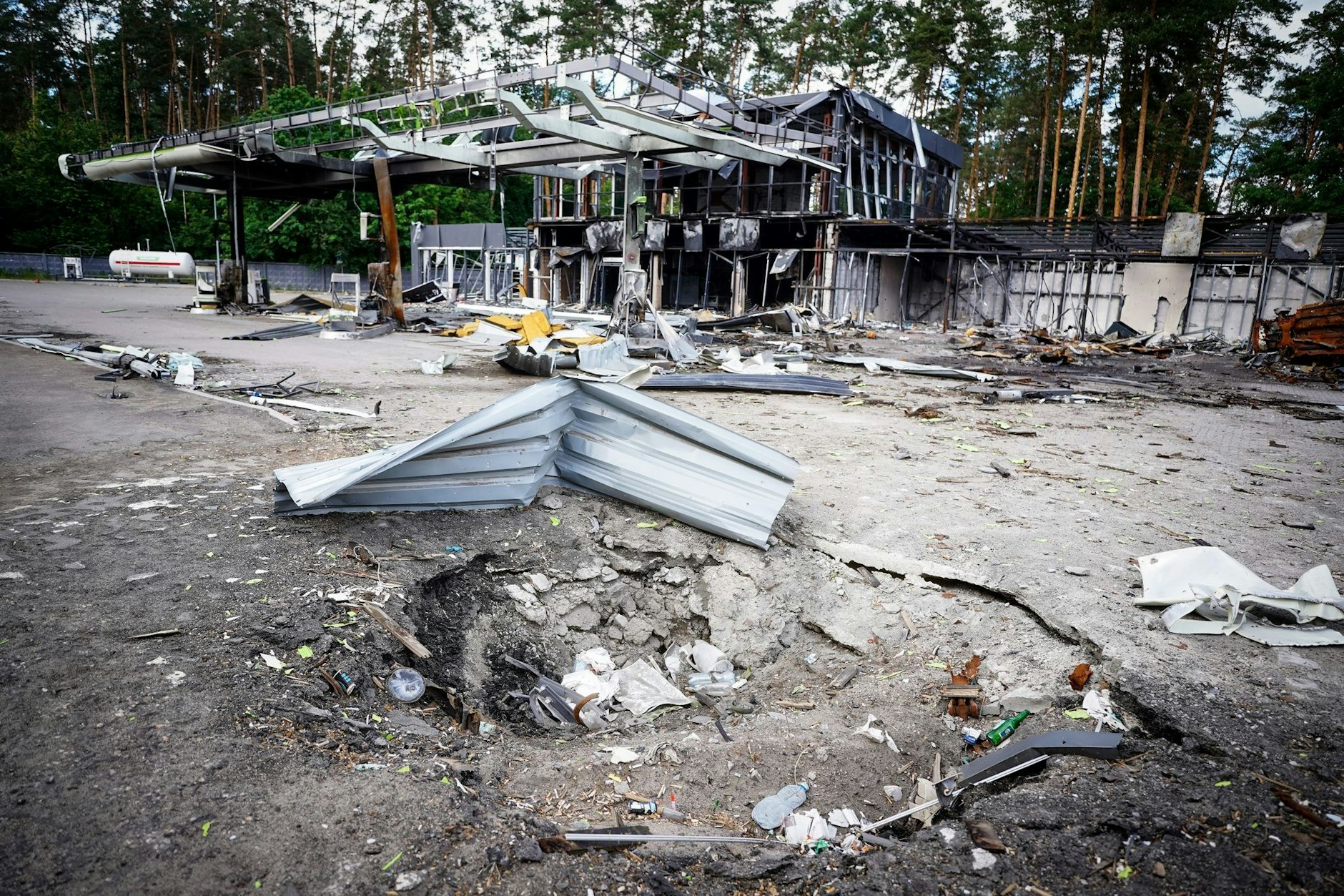 Ein Bombenkrater vor einer zerstörten Tankstelle am Stadtrand der ukrainischen Hauptstadt Kiew
