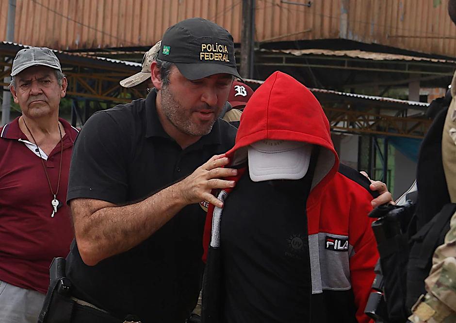Ein Bundespolizist eskortiert einen Verdächtigen in dem Gebiet, in dem der indigene Experte Bruno Pereira und der freiberufliche britische Journalist Dom Phillips verschwanden.  