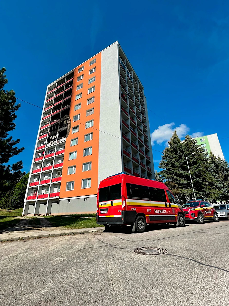 Einsatzfahrzeuge stehen vor dem Wohnhaus, in dem ein Feuer im fünften Stock ausgebrochen war.  
