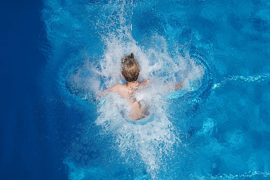 Ein Junge springt in einem Freibad ins Wasser.  