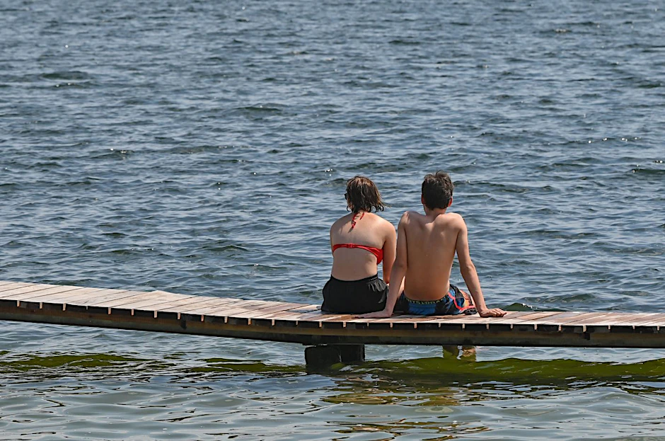 Zwei Sonnenanbeter sitzen am Storkower See in Brandenburg.