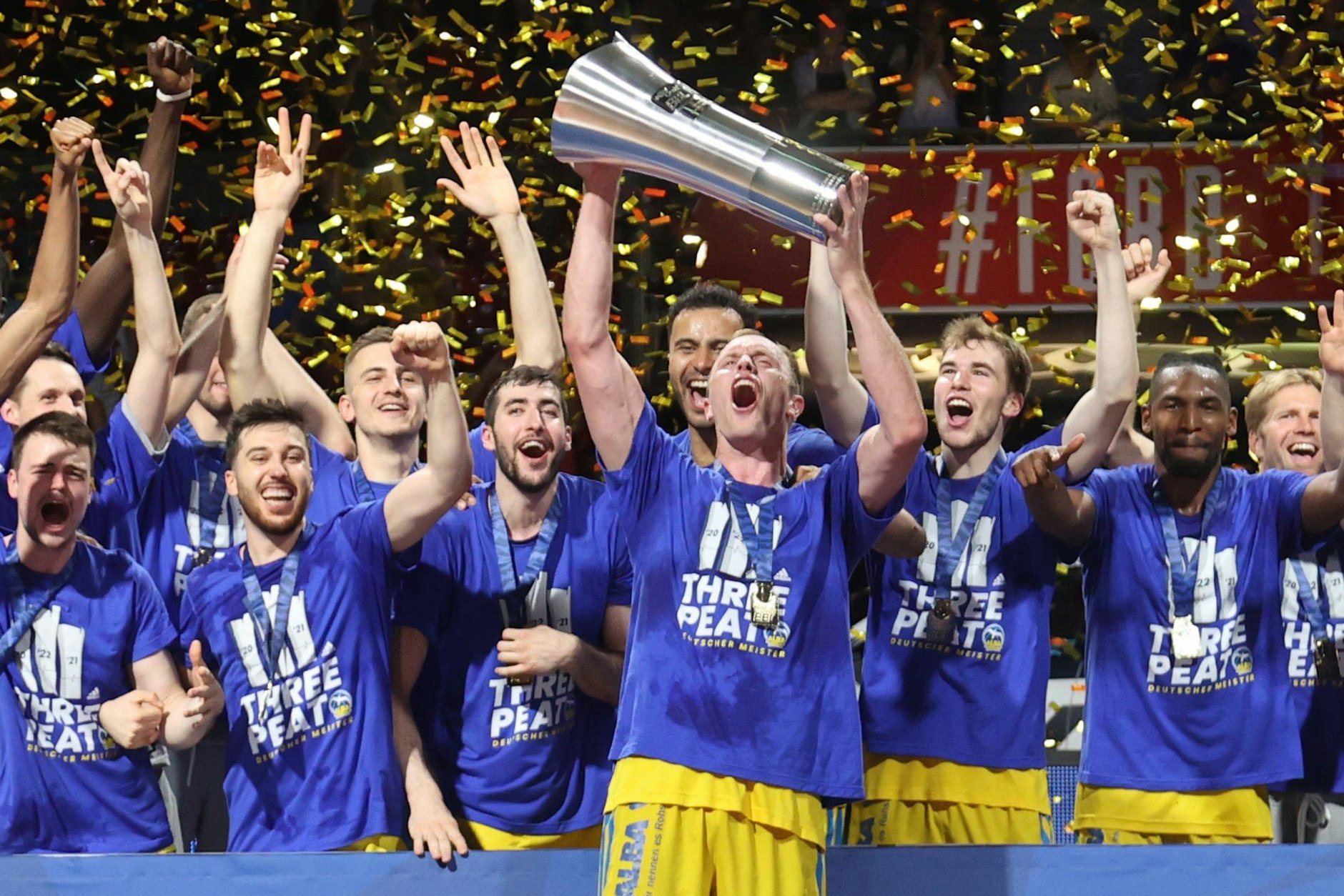 Im Konfettiregen stemmt Alba-Kapitän Luke Sikma den Meisterpokal, seine Kollegen jubeln mit.