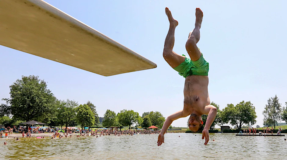 Hitze auch am Sonntag: Ein Mann springt kopfüber von einem Sprungbrett in das Wasser.  