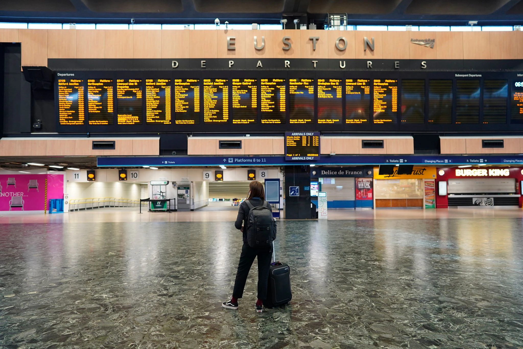 Ein Fahrgast steht im Bahnhof Euston und blickt auf die Anzeigetafel während eines Streiks.  