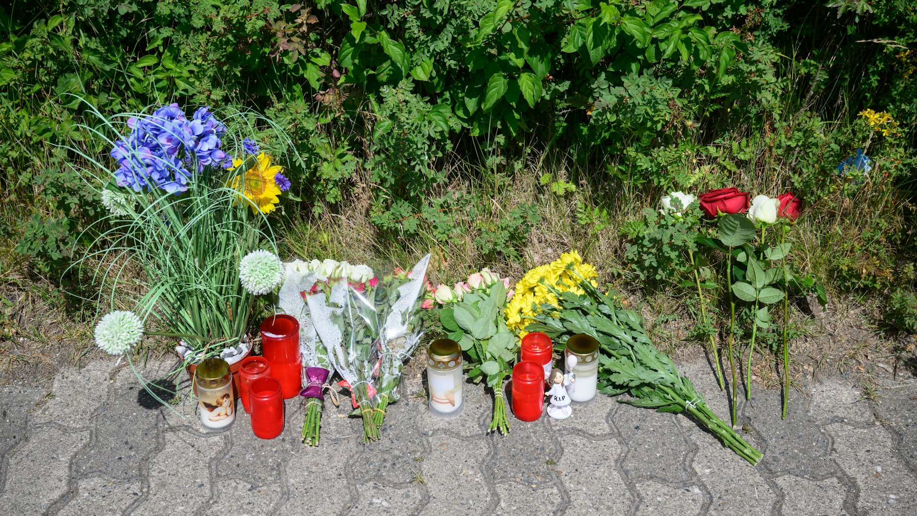 Am Rand der Gründfläche, wo die Leiche des 15-jährigen Mädchens gefunden wurde, haben Trauernde Kerzen, Blumen und Engelfiguren abgelegt.