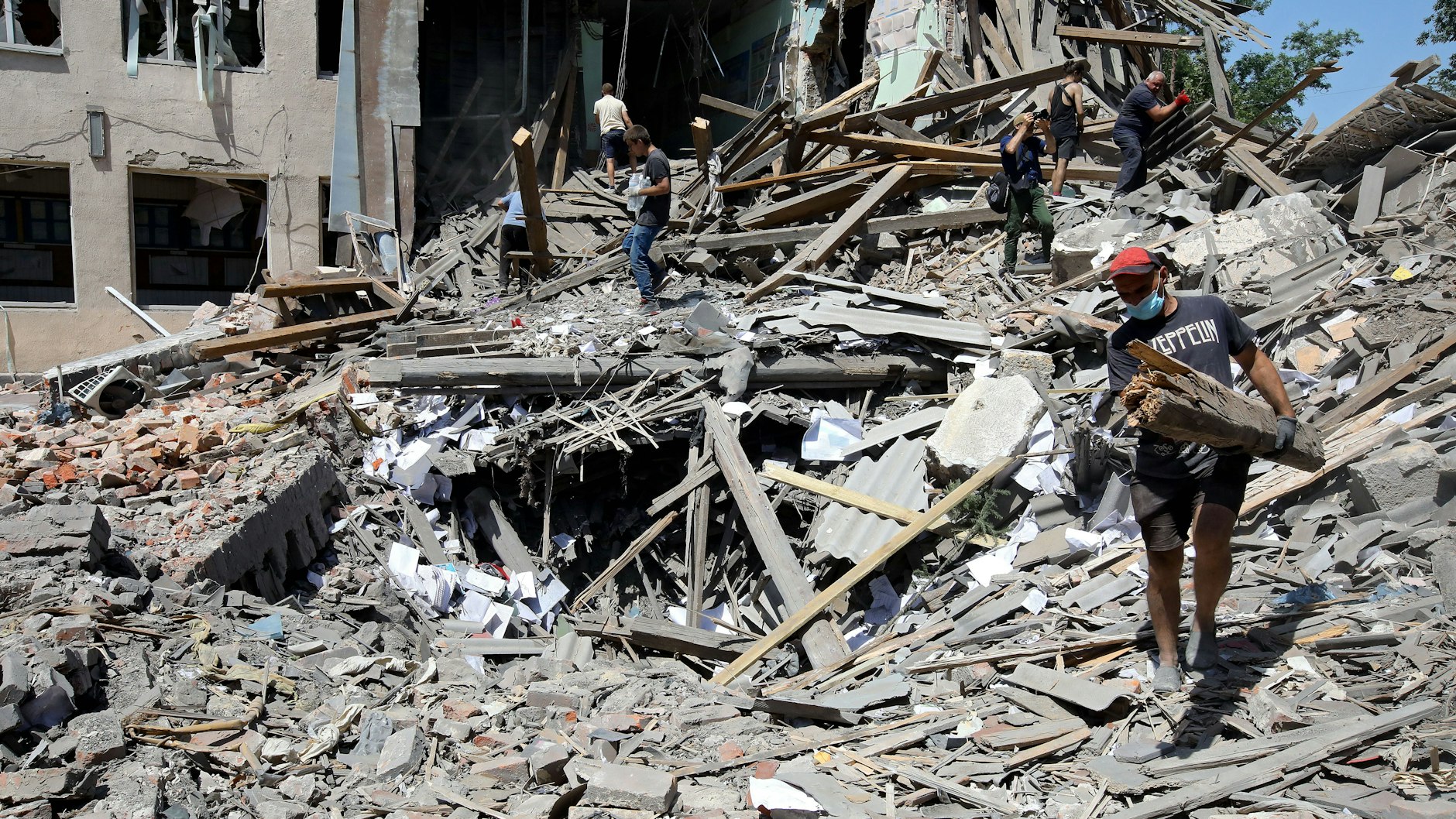 Einwohner im Schutt eines von einer russischen Rakete zerstörten Hauses in Liubotyn in der Region Charkiw.